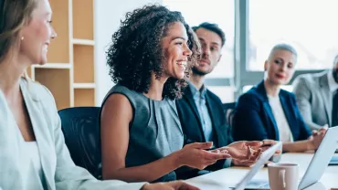 Five white-collar professionals of different genders and ethnicities seated in an office environment